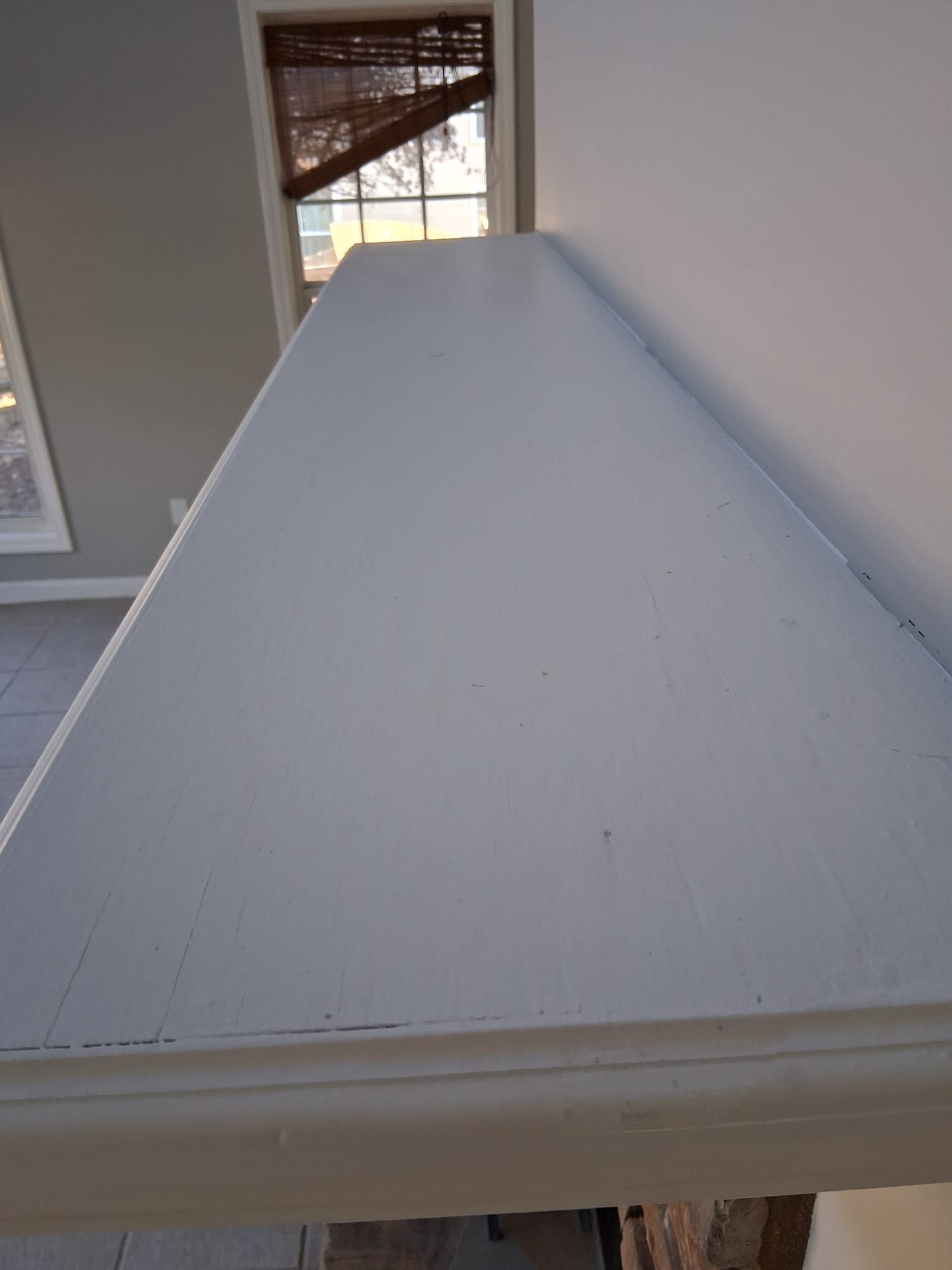 Close-up of a high white shelf being cleaned, showing dust marks and surface details near a window, representing detailed deep cleaning of hard-to-reach areas in a home.