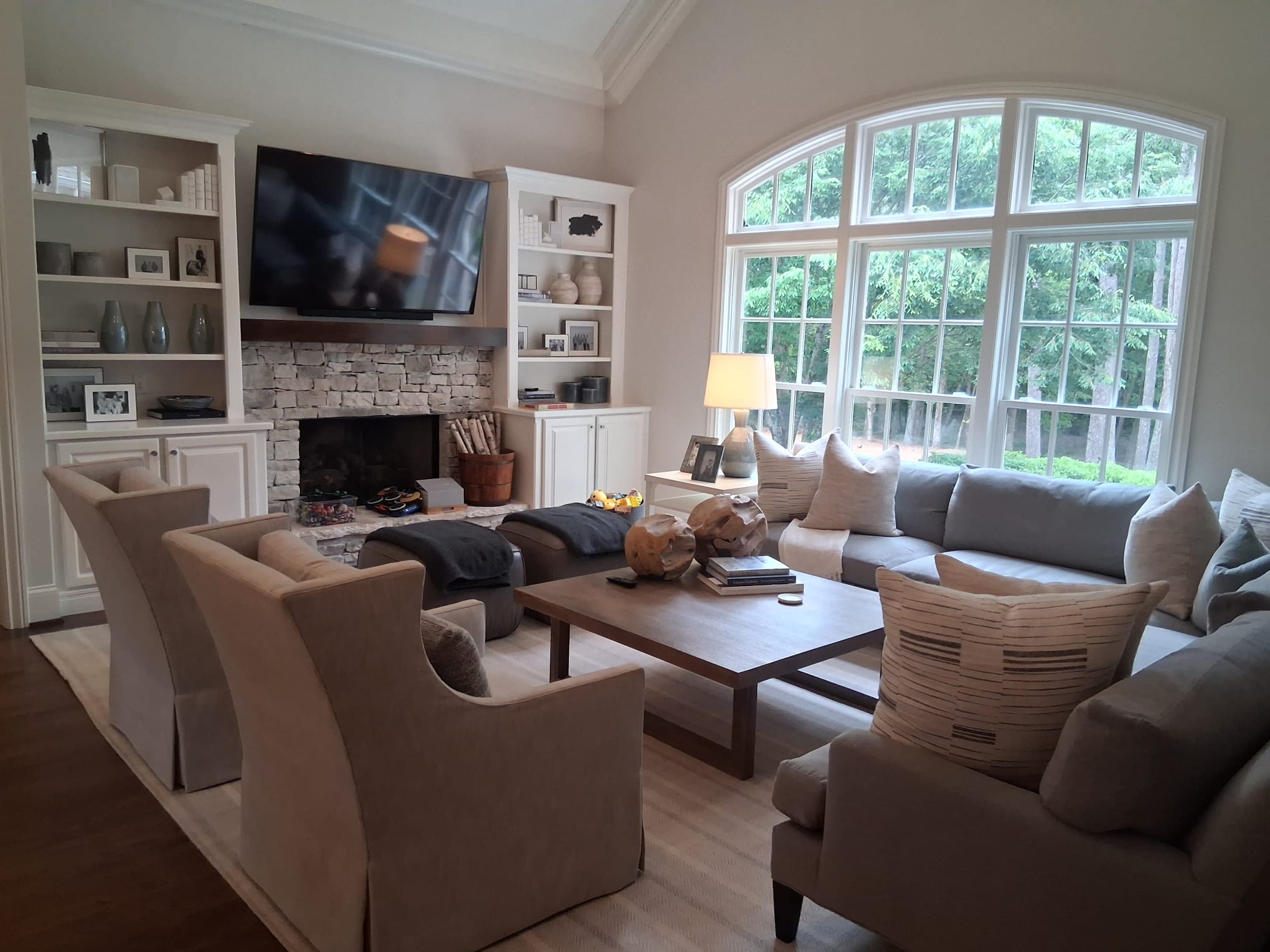 Regular living room cleaning with fireplace, built-in shelves, sofas, furniture, hardwood floors, and large windows